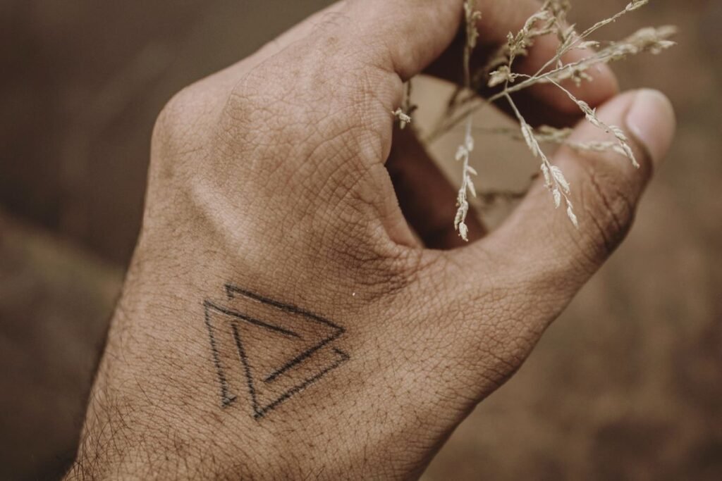 Kleines Dreieck als minimalistisches Tattoo auf einem Handrücken